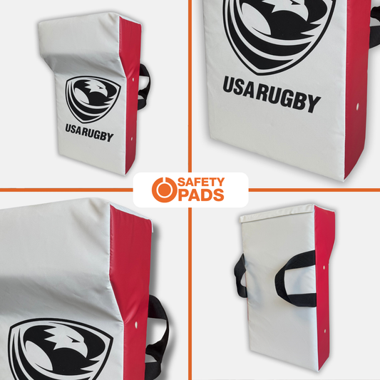 Four views of a USA Rugby safety pad on a white background, showing the white body, red side panel, black logo, and black carrying handles. A central label reads 'SAFETY PADS'.