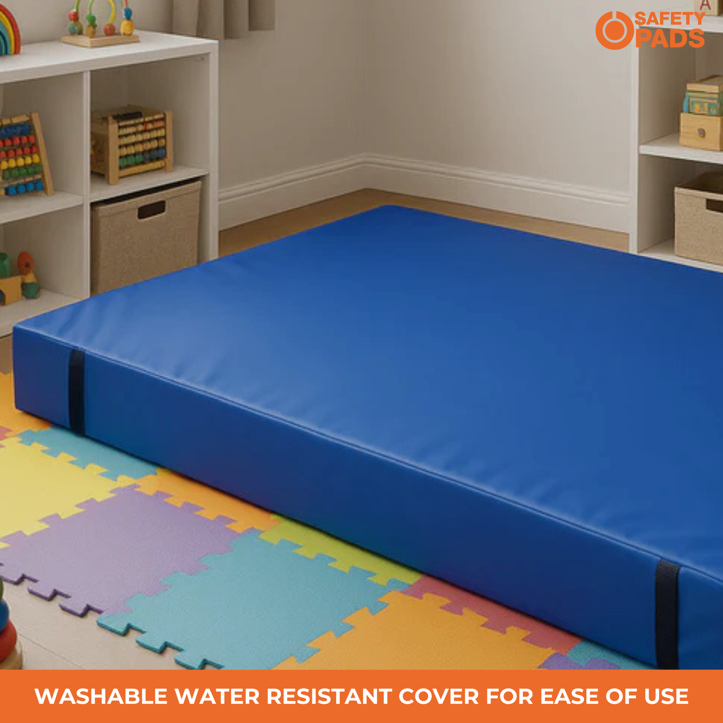 A blue foam safety mat or mattress cover shown in a children's room setting with colorful floor mats, white shelves, and toys. An orange 'SAFETY PADS' logo appears in the top right, and a text banner at the bottom reads 'WASHABLE WATER RESISTANT COVER FOR EASE OF USE'.